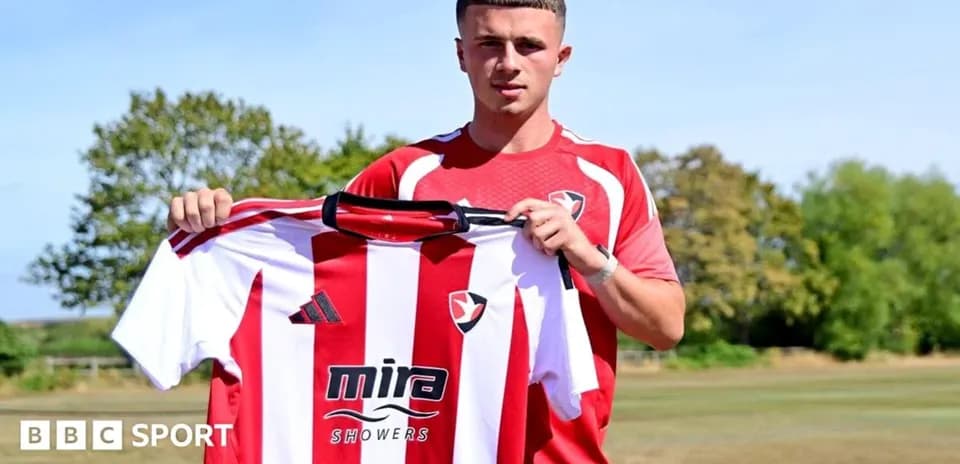 Игрок держит футболку Cheltenham Town на тренировочном поле