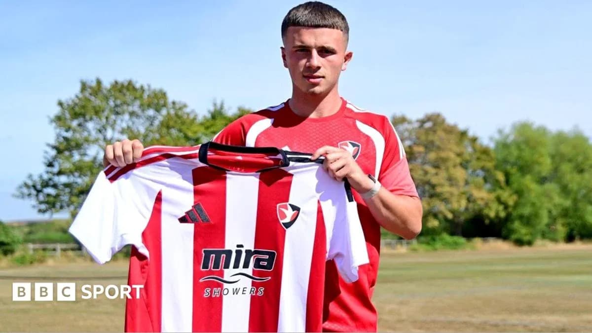 Игрок держит футболку Cheltenham Town на тренировочном поле