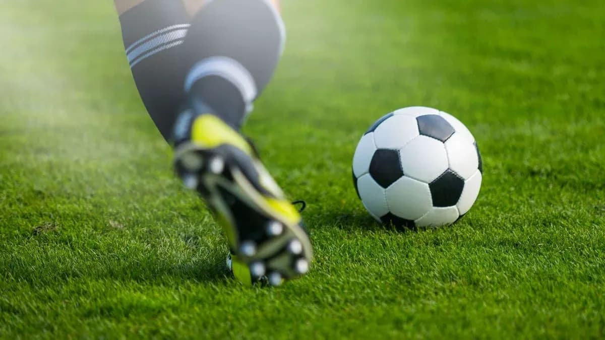 Игрок бьет по мячу на травяном поле