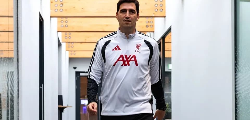 Человек в тренировочной одежде Liverpool FC идет по коридору