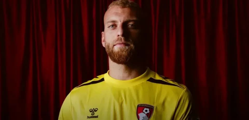Игрок в желтой форме AFC Bournemouth на фоне занавеса