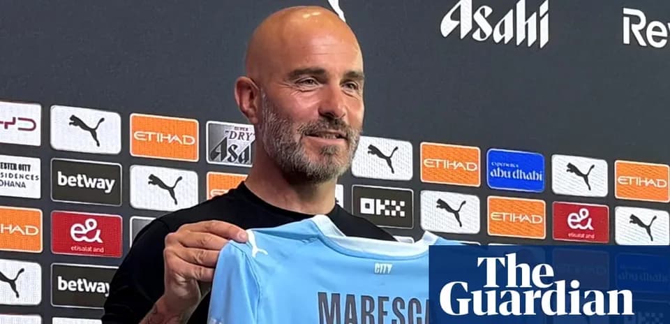Тренер показывает футболку клуба Manchester City