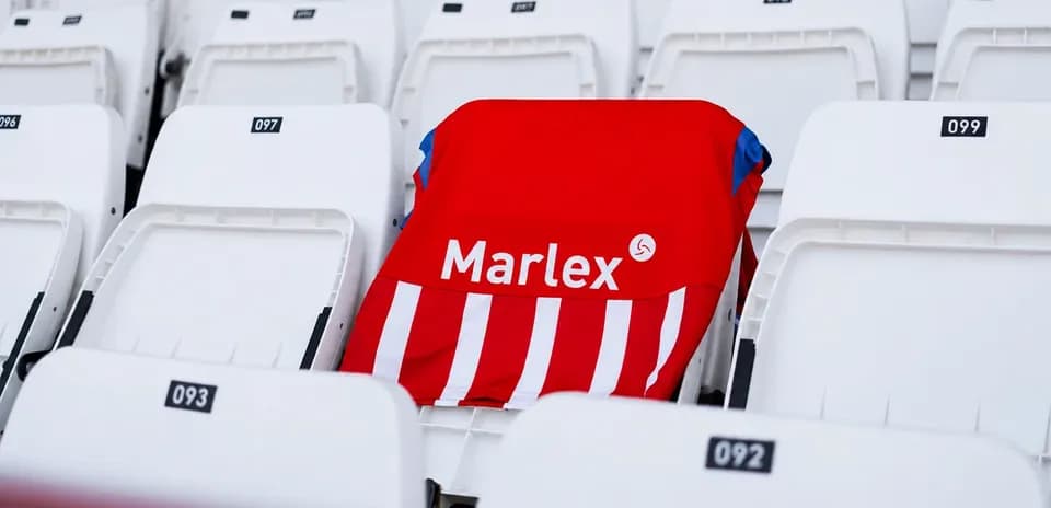 Красная футболка Marlex на пустом стуле стадиона