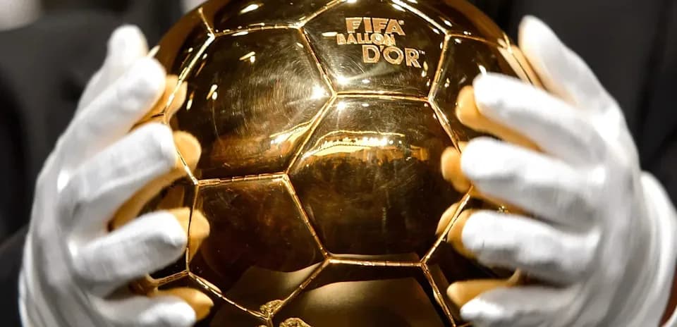 Человек держит золотой мяч FIFA Ballon d'Or