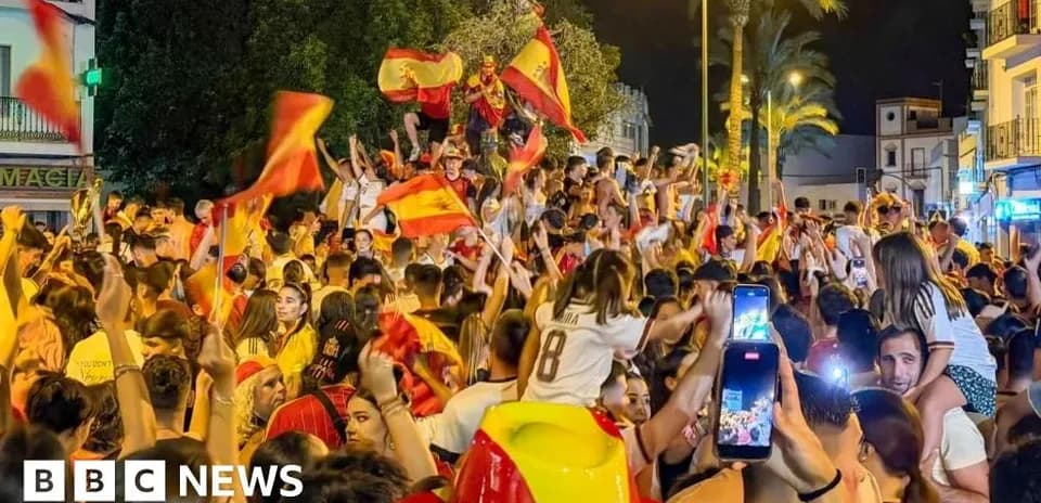 Толпа людей празднует с флагами Испании на улице