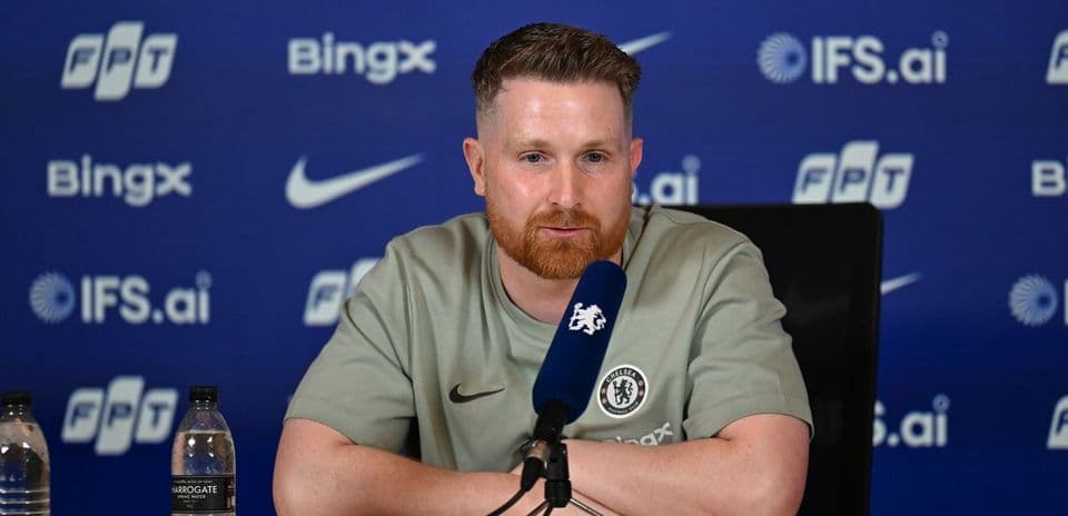 Человек на пресс-конференции с логотипом Chelsea