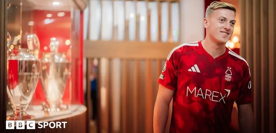 Игрок в красной форме Nottingham Forest рядом с трофеями