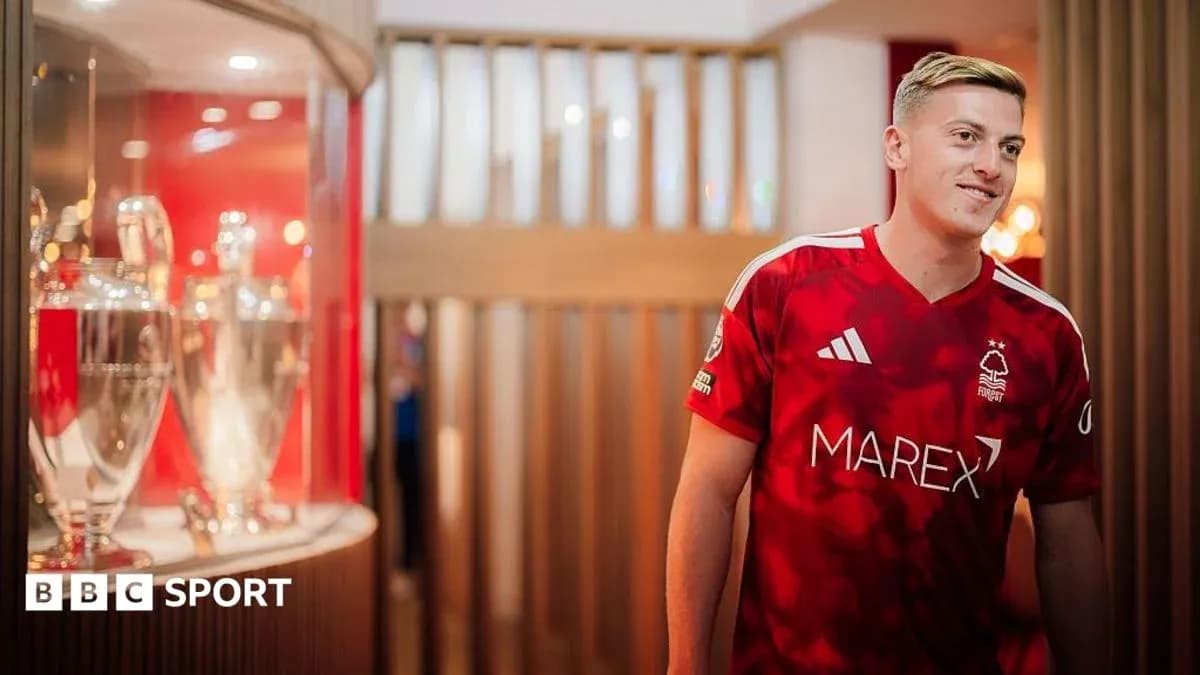 Игрок в красной форме Nottingham Forest рядом с трофеями