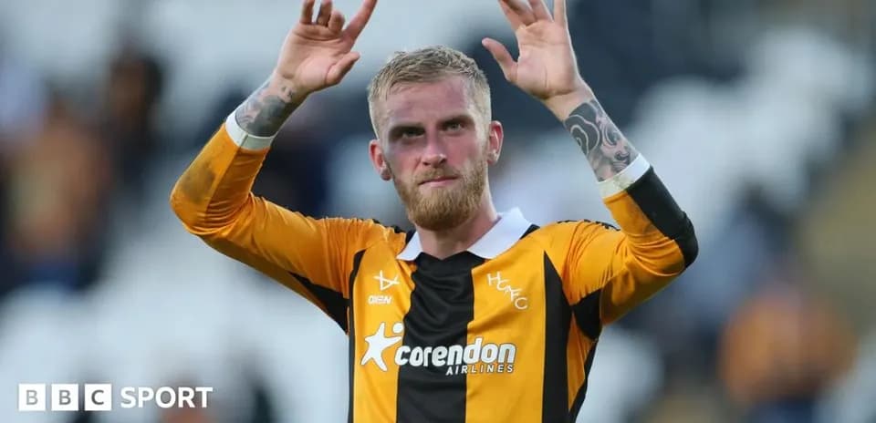 Игрок команды HFC с поднятыми руками на стадионе