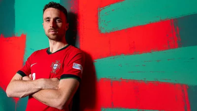 Игрок сборной Португалии позирует на фоне флага