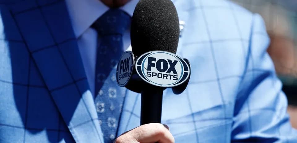 Микрофон FOX Sports в руке человека в костюме