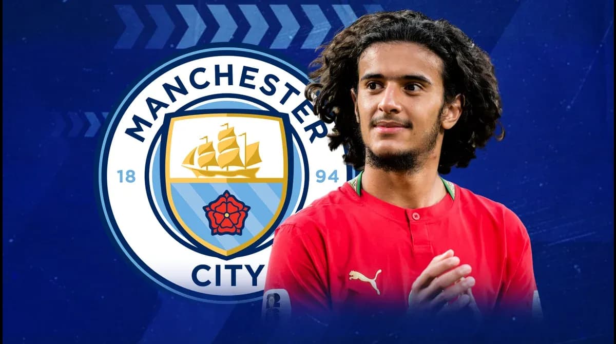 Игрок в красной форме на фоне логотипа Manchester City Игрок в красной форме на фоне логотипа Manchester City