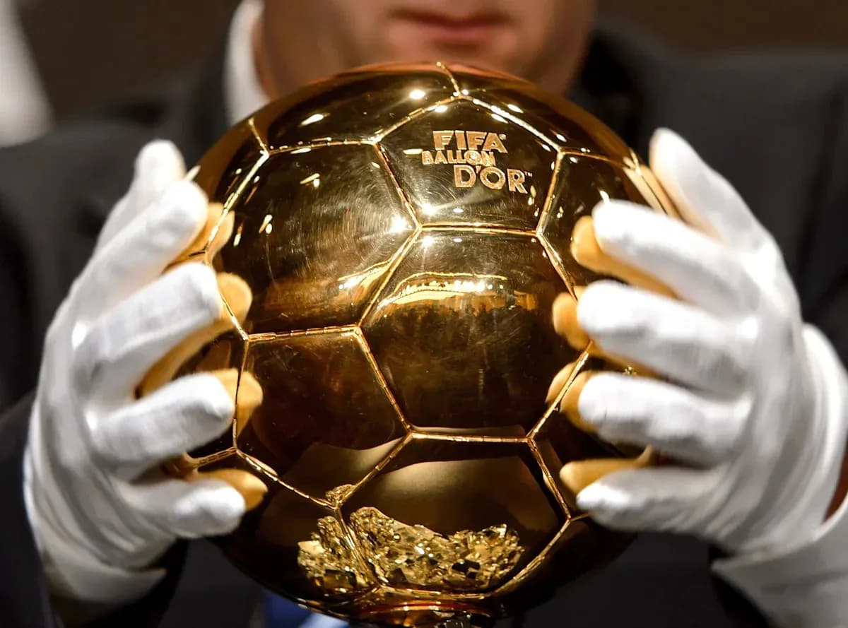 Человек держит золотой мяч FIFA Ballon d'Or Человек держит золотой мяч FIFA Ballon d'Or
