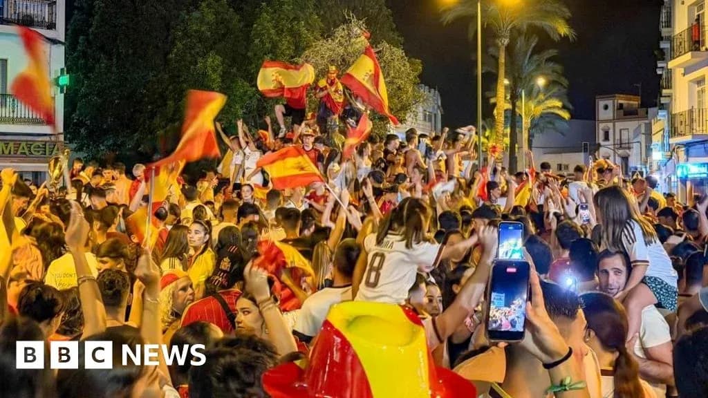 Толпа людей празднует с флагами Испании на улице Толпа людей празднует с флагами Испании на улице